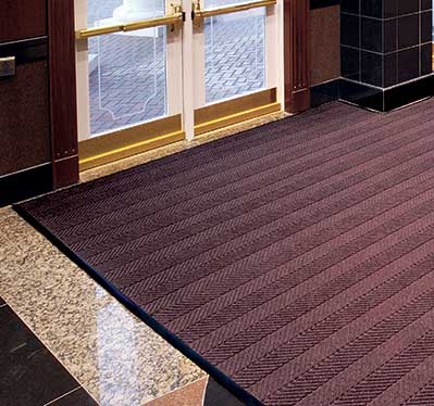 Waterhog commercial entrance mat at building doorway designed to trap dirt and absorb moisture in high-traffic areas