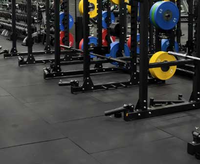 Commercial gym flooring with heavy-duty rubber mats supporting strength training equipment and weight areas.