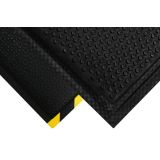 Black nitrile Happy Feet anti-fatigue mat with yellow striped border at an industrial workstation
